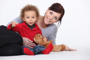 A woman and child sitting on the ground with teddy bears.