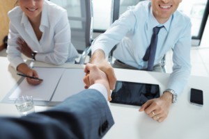 A man shaking hands with another man in front of two other men.