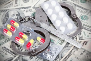 A pair of handcuffs and pills on top of money.