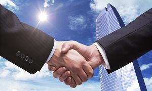 Two men shaking hands in front of a building.