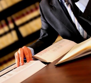 A person in suit and tie at desk with book.