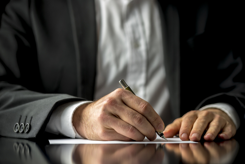 A man writing on paper with pen and ink.